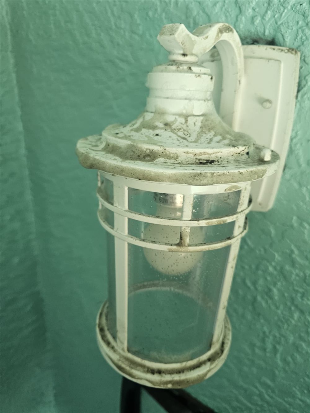 Outdoor light fixture before cleaning, covered in dust and grime buildup