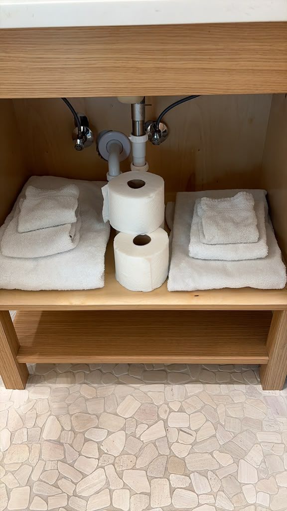 Restocked towels and toilet paper under a vacation rental bathroom sink
